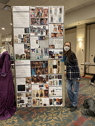 "young woman standing next to a floor-to-ceiling print out of her costume and scenic designs and the thought process behind them."
